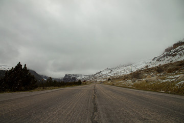 Fototapeta premium A lonely cold winter road leading towards snowy mountains in Wyoming