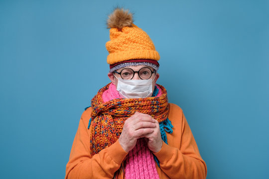 Mature man with medical mask as protection from Covid-19 and funny hat glasses and scarf.