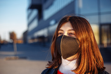 Portrait of a young girl in a black medical sterile mask staying safe from coronavirus. Prevent spread of covid-19 virus during quarantine. Girl looks forward to epidemic pandemia end.