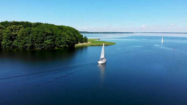 Aerial view of sailboat on the beautiful lake Kisajno on a sunny day. Mazury by drone, Poland