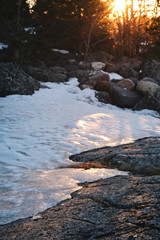 Ice on a cliff with the sun and forest in the background