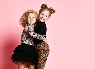 Laughing kids girls friends sisters in leopard print clothes pants and sweater are running jumping...