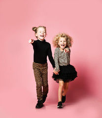 Laughing kids girls friends sisters in leopard print clothes pants and sweater are running jumping...