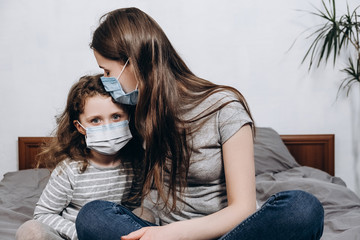 Portrait unhealthy young caucasian family wearing medical face mask sitting on bed at home, concept of coronavirus or COVID-19 pandemic disease symptoms, flu and viral infections, healthcare