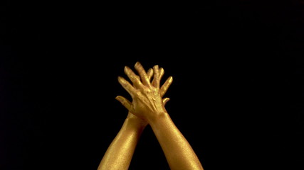 Nice footage of woman gold hands gesture. Black background. Hands in gold color paint on black background.