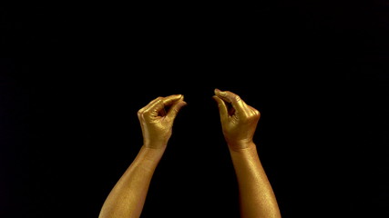 Nice footage of woman gold hands gesture. Black background. Hands in gold color paint on black...
