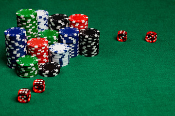 Large copy writing space with betting chips and 4 translucent red casino style dice on a green felt playing surface.  Vivid colors and contrast.