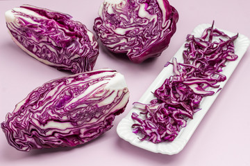 Halved red cabbage, sliced cabbage on on white plate.