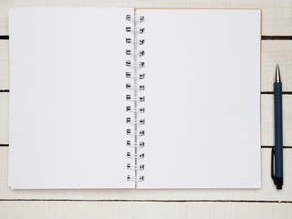 Workplace - notebook and pen for remote work on a white wooden table. Freelance desktop for home or office. Background with copy space.