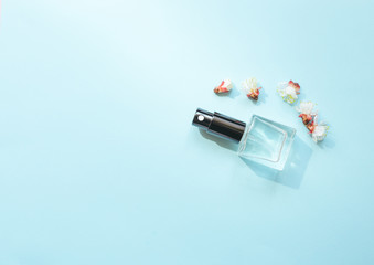 Composition with bottle of perfume and blooming flower on cyan background. Aromatherapy concept with  top  view and copy space Flat Lay.