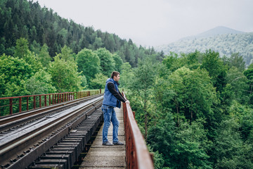 Young man on railway track on forest background. The observation deck.