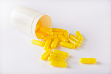 A pile of yellow capsules on a white background, isolate. Bottle of pills sprinkled