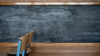 Empty blackboard in a classroom in school with wooden chairs and table