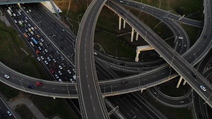 Aerial drone view of highway multi-level junction road with moving cars at sunset. Cars are moving on a multi-level road junction