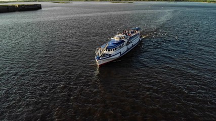 Obraz premium Cruise ship sailing across river - aerial footage. A lot of seagulls near the liner
