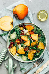 healthy delicious winter salad with persimmon slices, mix of spinach, arugula and lettuce leaves with blue cheese and walnuts