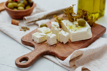 Fresh Greek Feta Cheese with olives. Healthy ingredient for cooking salad. Chopped Goat feta cheese on cutting board.