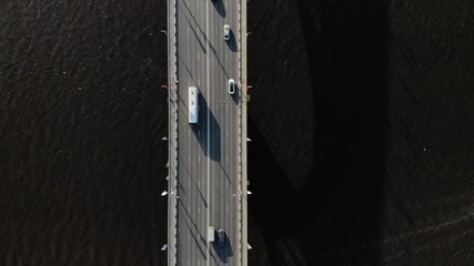 Straight down drone footage of bridge in middle of canal or lake separating sea from sweet water. Commuter or tourist traffic vehicles and cars drive by