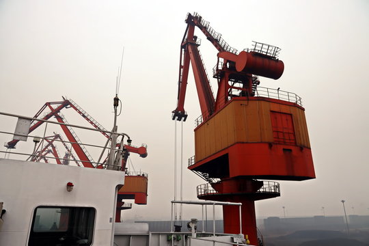 Cargo terminal for discharging coal cargos by shore cranes during foggy weather. Port Bayuquan,China. January, 2020.