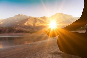 Human silhouette meditating at sunset background