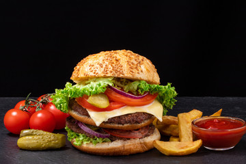 Big burger with french fries on dark background