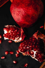 drones of ripe pomegranate. red ripe juice. cinnamon on a black background