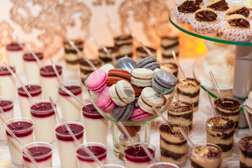desserts with mousse, biscuits. Different types of sweet pastries, small colorful sweet cakes, macaron, and other desserts in the sweet buffet. candy bar for birthday, wedding party