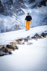 Winter sports - young man running with snowshoes downhill in high mountains covered with lots of snow