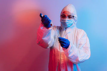 A young doctor in medical uniform with a protective face mask and a gloved hands filling injection...