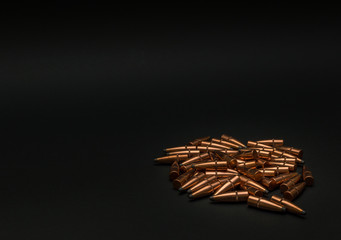Unloaded hunting bullets laying in a pile on a black background with room for text
