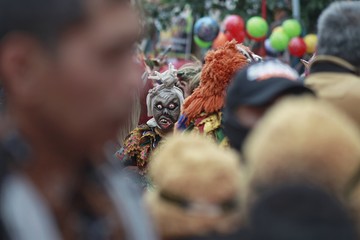 A teenager wears a scary Indonesian ghost mask commonly called Pocong in a cultural carnival