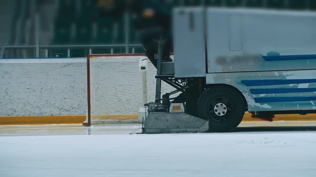Zamboni resurfacing an indoor skating rink. Slow Motion. Ice resurfacer cleaning ice, machine cleaning and polishing smooth icerink. Ice harvester or restores ice.