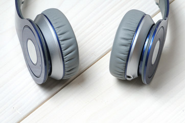 Blue and silver modern headphones on a white wooden background