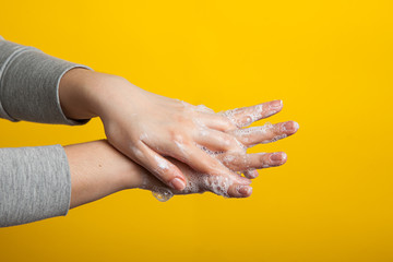 female hands hold soap hands between fingers on a yellow studio background. Bright close-up photo. Instructions for proper hand washing.