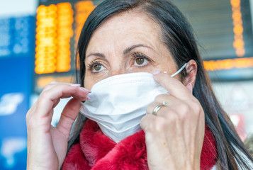 Coronavirus outbreak emergency. Woman in Italy wearing a mask in front of train timetable