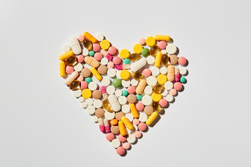 Colorful assorted heart shaped pills pattern  flat lay of medicine pills colorful medicine on white background. Health care concept
