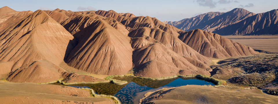 aerial landscape of the amazing Ozero Torpo, a lake surrounded by eroded mud hills along the Mels-Ashu pass connection Tash-Rabat at the village of Baetov