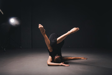 Portrait of a beautiful woman dancing on black background. Ballet and contemporary dancer dancing on dark backdrop. Contemporary Art. Plastic and flexible girl in black clothes posing on a black wall