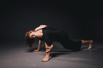 Portrait of a beautiful woman dancing on black background. Ballet and contemporary dancer dancing on dark backdrop. Contemporary Art. Plastic and flexible girl in black clothes posing on a black wall