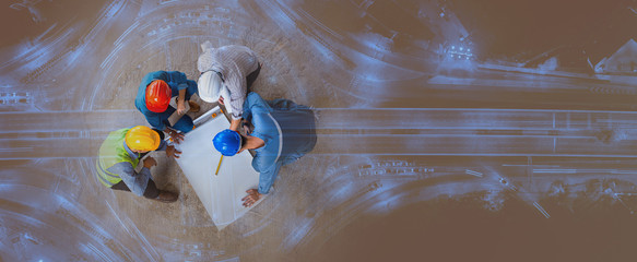 Top view of architectural engineer working on his blueprints with documents on construction site....