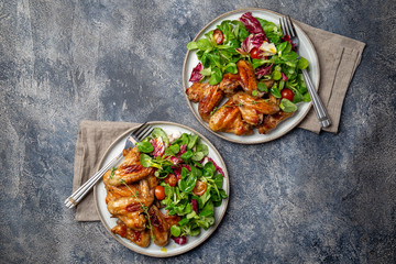 Roasted bbq wings with green salad with tomatoes. Top view