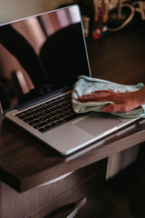 Woman disinfects and cleans laptop keyboard at home, with antibacterial wet wipe to protect from viruses, germs and bacteria during the coronavirus outbreak, covid ncov epidemic. Clean laptop