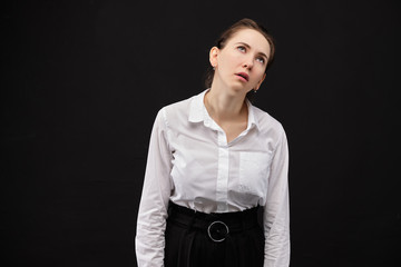 A girl in a white shirt on a black background is a very tired workaholic.