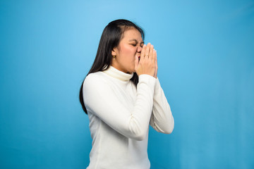 Portrait of Young beautiful asian women using white T-shirt with blue isolated background, sneezing due to symptoms of corona virus, Covid-19,  sneezing coronavirus