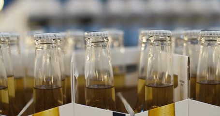 Close up of glass bottles with beer in carton boxes on supermarket shop shelf. Tops of alcohol drinks. Cyder in shop. Cider on retail concept.