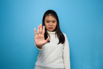 Portrait of Young beautiful asian women using white T-shirt with blue isolated background, reject gesture
