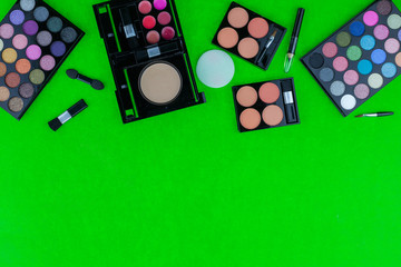 Professional multi colored eyeshadow makeup palette and brushes on green background copy space for your text.