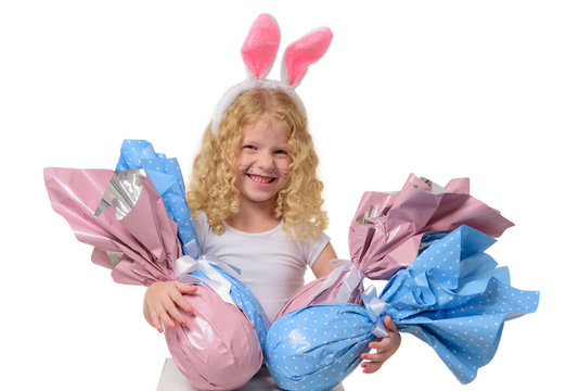 Cute little girl in the Easter bunny ears hugs Easter eggs on isolated white background. The child smiles. Copy space.