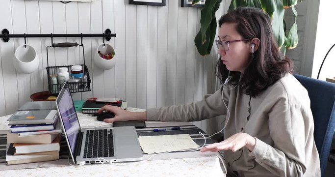 Young asian woman at home office look at camera of her laptop and doing online interview during video chat conference call. teaching student on webinar in app via internet connection