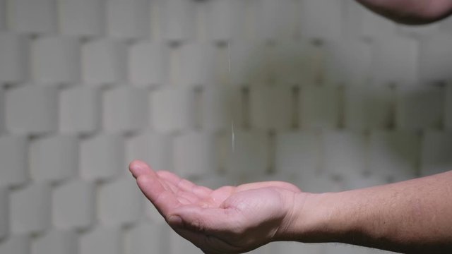 Man Spilled Disinfectant On Hands. Background Wall Of Toilet Paper Rolls. 4K Slow Motion Footage